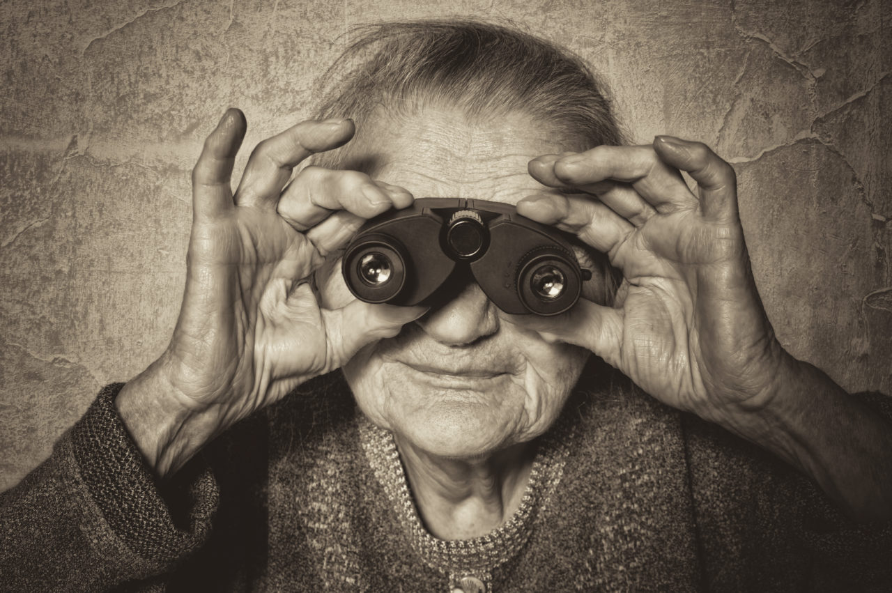 Elderly woman looks through binoculars.